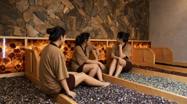Nhóm khách nghỉ trong phòng Jjimjilbang với nền đá và sỏi tại AMARE